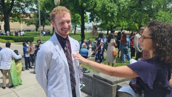 UC Davis health professions post-bac grad Drew Meyers poses in his white coat