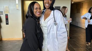 UC Davis health professions post-bac Eyonna Woghiren poses in her white coat with program director