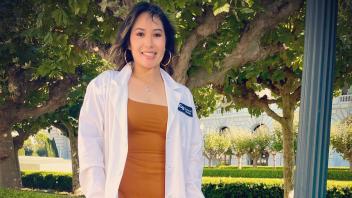 UC Davis Post-Bac grad Monneca Rim poses in her white coat for dental school