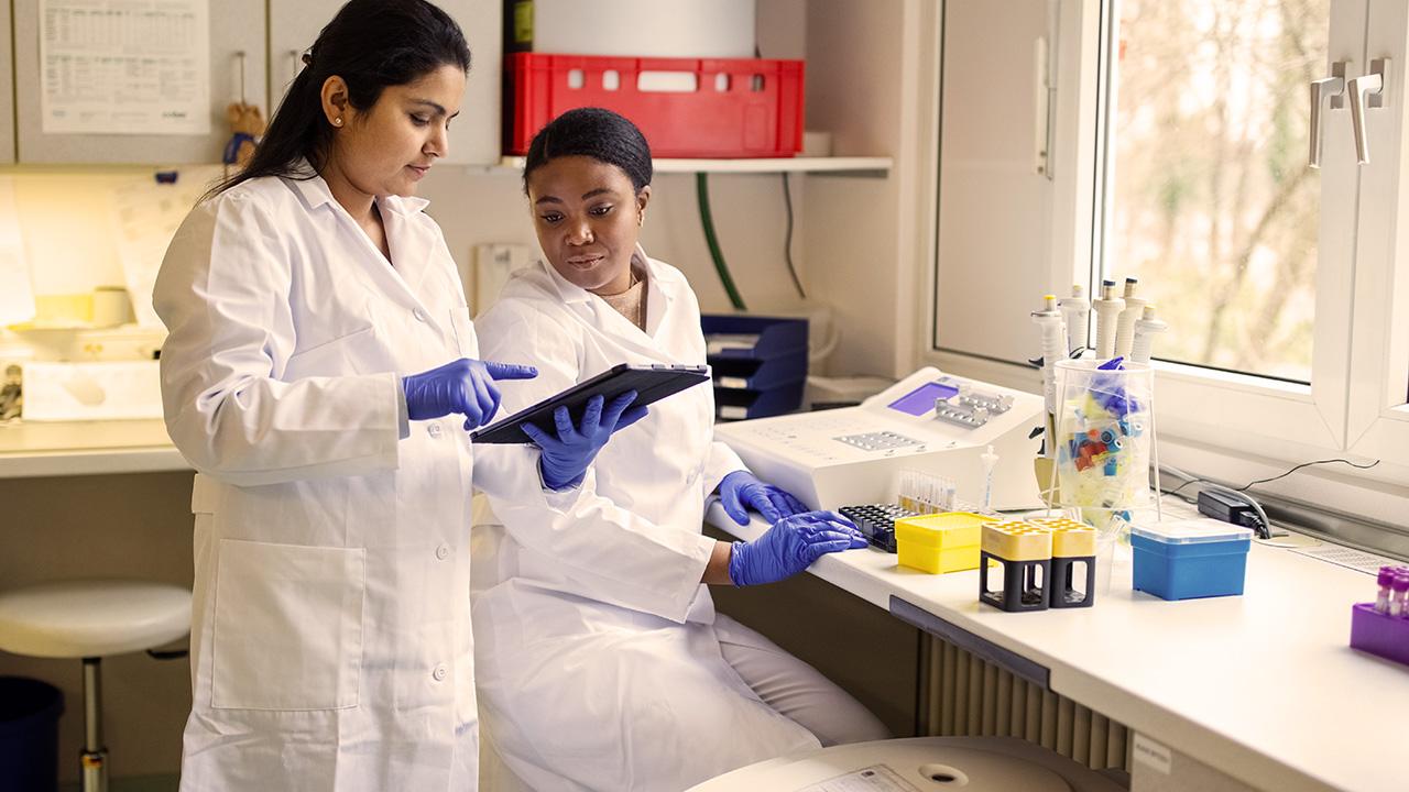 Two scientists discussing over a digital tablet in lab