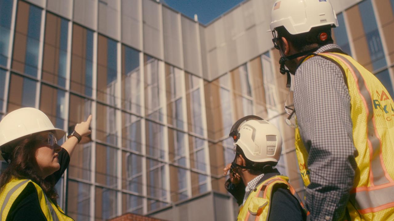 construction workers look up at a building