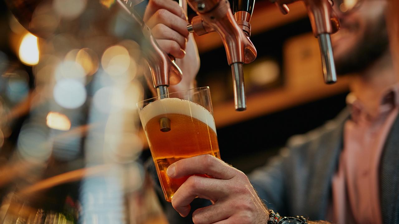 closeup of barman pouring beer while standing in pub