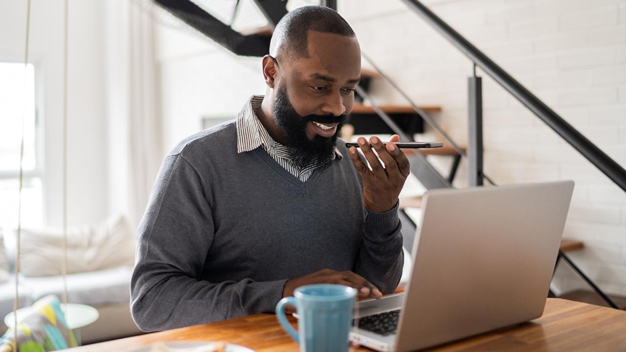 man sitting at home on laptop and phone