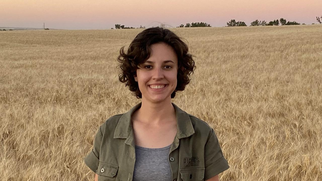 Emma Mechelke, winner of the Michael and Sheila Lewis Scholarship in brewing, poses in front of a field of wheat