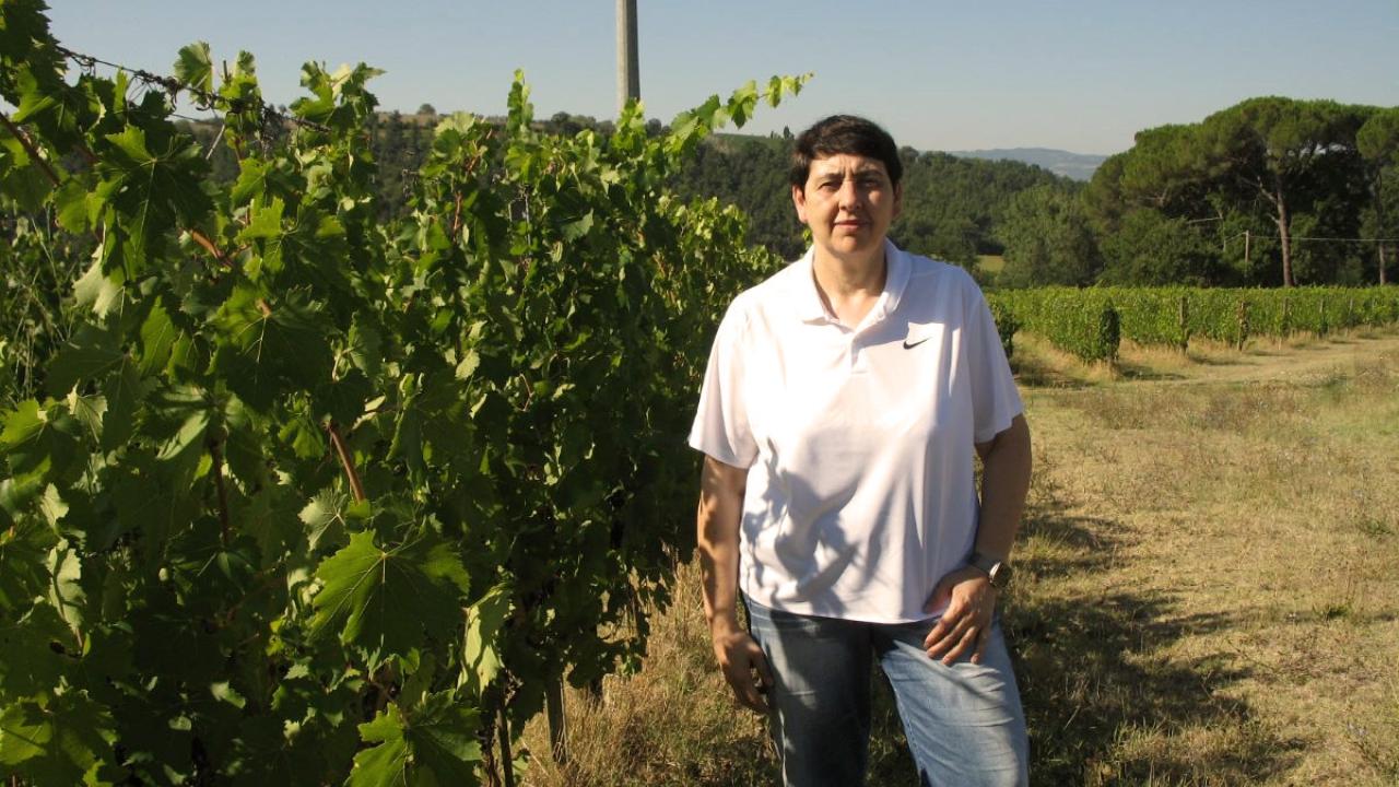 UC Davis Winemaking Certificate grad Mariachiara poses in front of vineyards near her house in Fiorentini