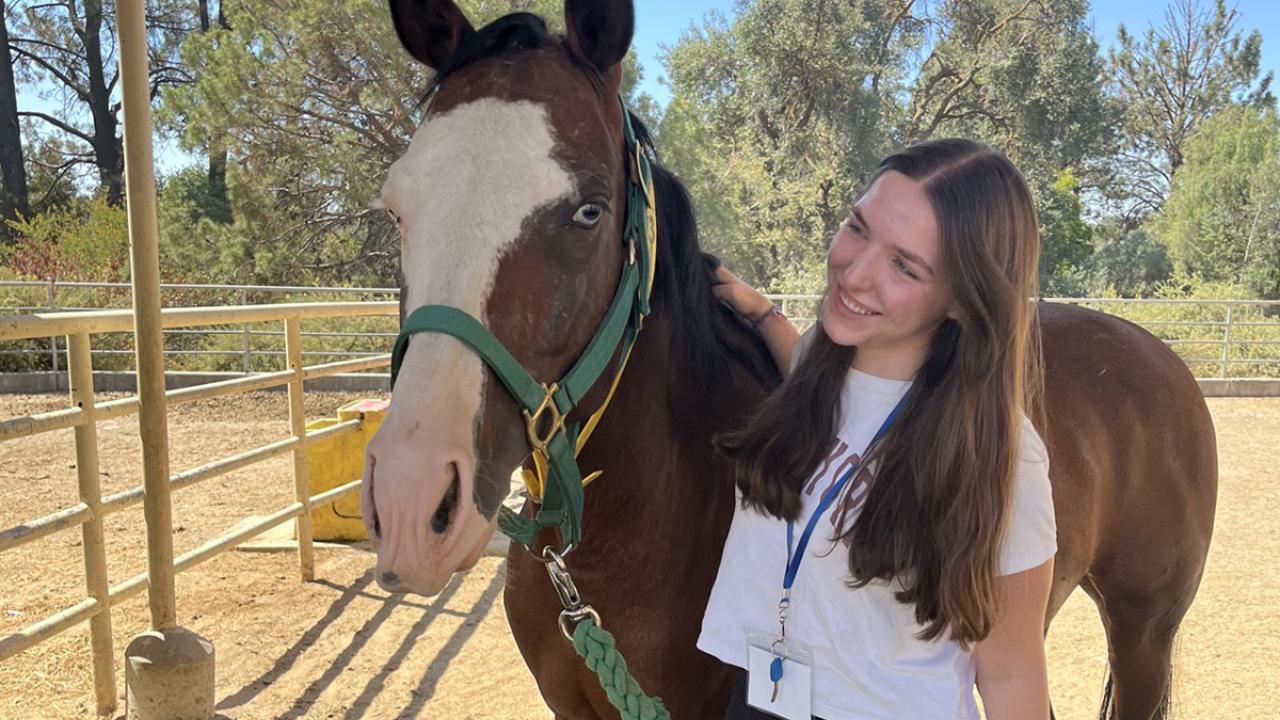 UC Davis Pre-College student poses with a horse