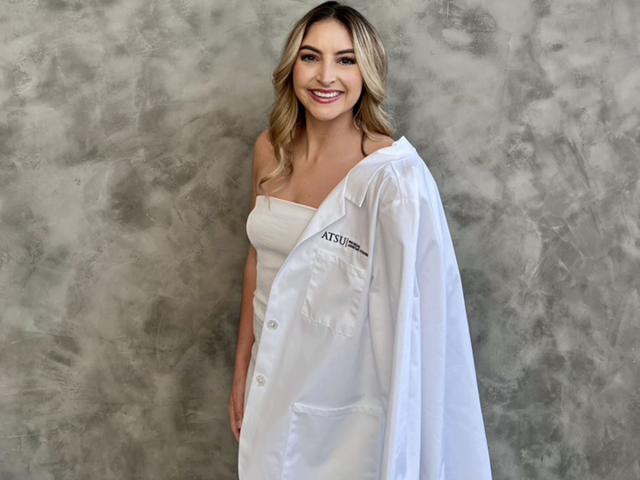 UC Davis Health Professions Post-Bac student Gabby Rich poses in her white coat
