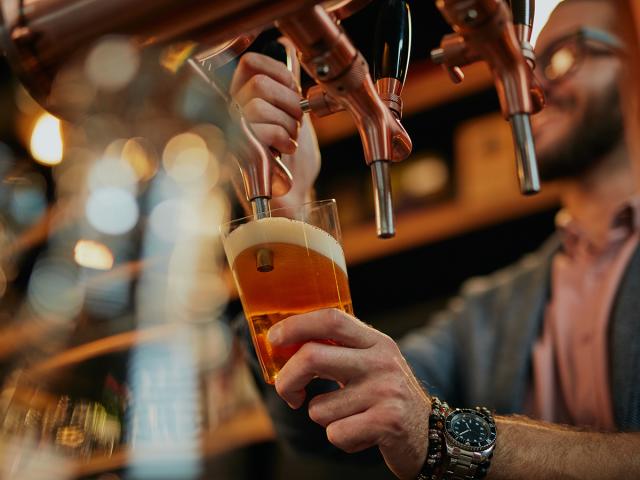 closeup of barman pouring beer while standing in pub