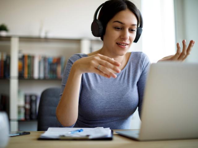 A woman on headphones at a computer.