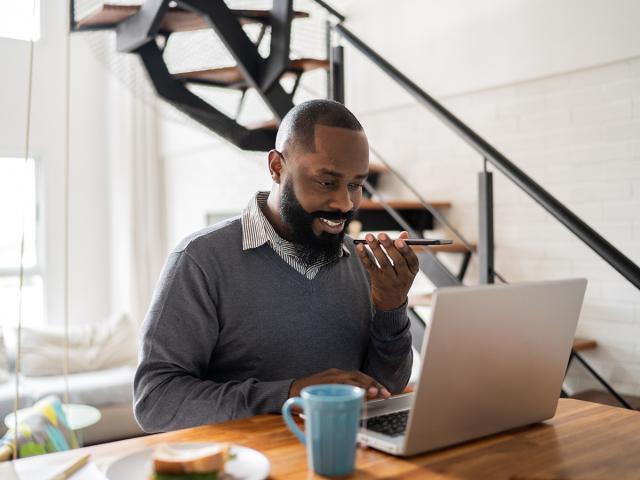 man sitting at home on laptop and phone