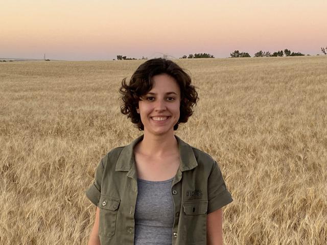 Emma Mechelke, winner of the Michael and Sheila Lewis Scholarship in brewing, poses in front of a field of wheat