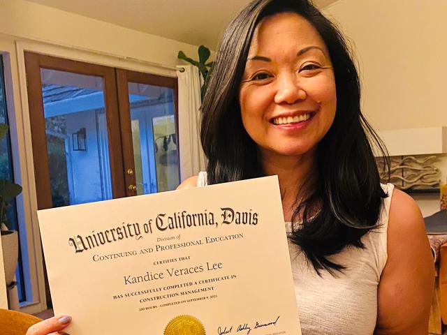 Kandice Lee smiles and holds her certificate showing that she has completed the Construction Management program