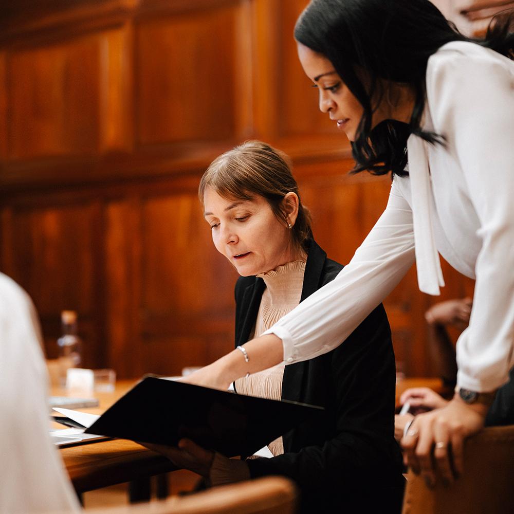 woman pointing out information in a file to a colleague in court