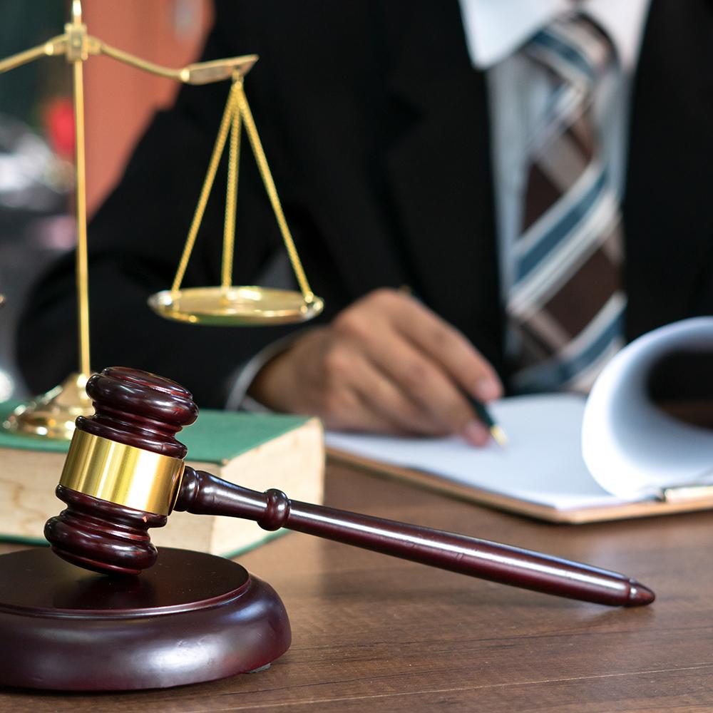man working at a desk in a law office with scales and gavel in the foreground