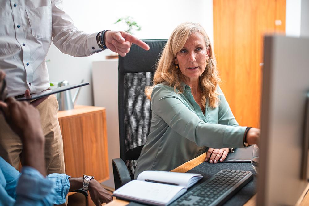 A woman and her colleagues analyze data on a computer