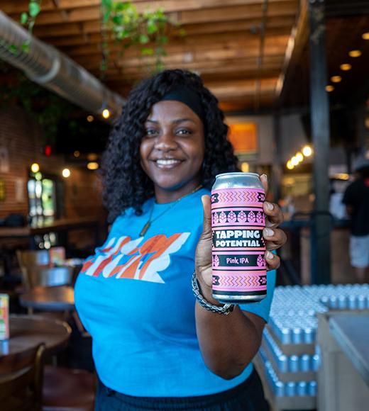 UC Davis Tapping Potential winner Chijindu Onwuchekwa poses in a bar with her Pink IPA can