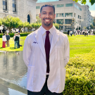 UC Davis Health Professions Post Bac grad Adejia Boutte poses in his white coat during his white coat ceremony for UCSF