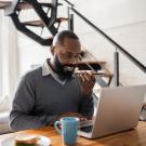 man sitting at home on laptop and phone