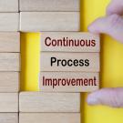 Hand pulling wooden blocks with continuous process improvement text. 