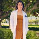UC Davis Post-Bac grad Monneca Rim poses in her white coat for dental school