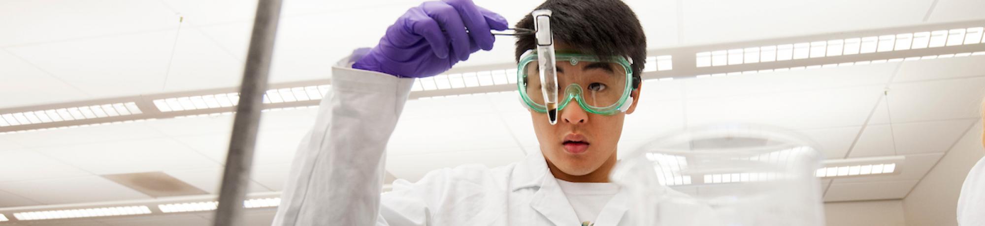 student in lab coat holding test tube
