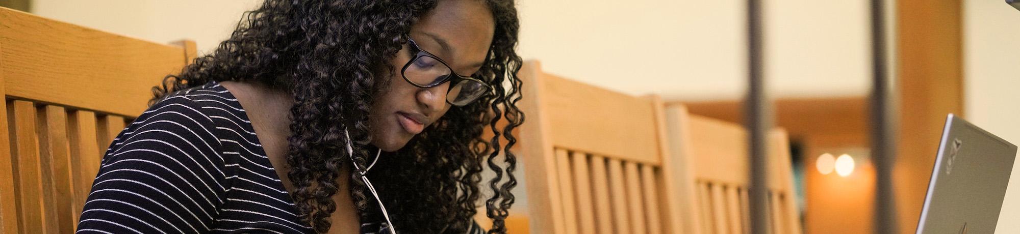 a student sits in the library on her laptop