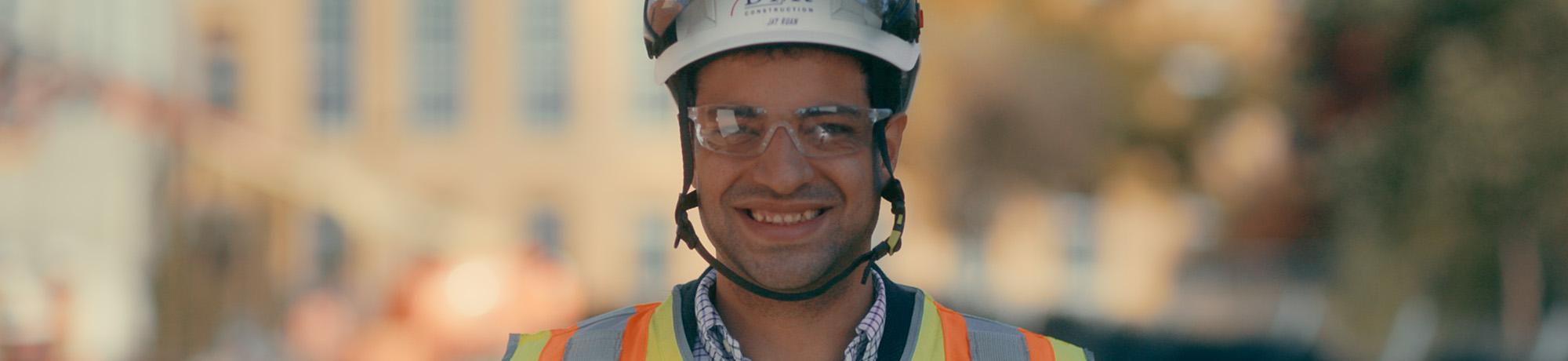 headshot of construction professional in helmet and vest smiling