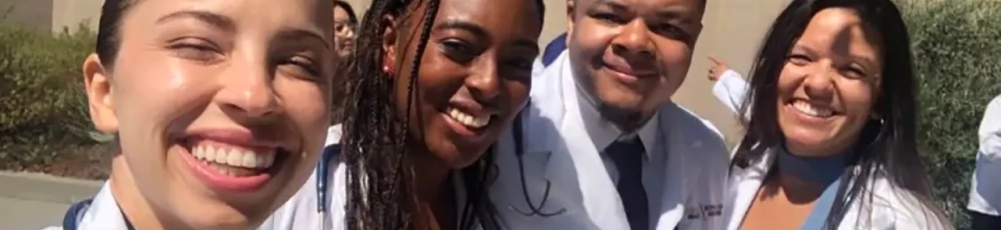 UC Davis Health Professions Post-bac grads Andre Brown, Matileen Cranick, Kayla Hall, Rachel Becker take a selfie in their white coat