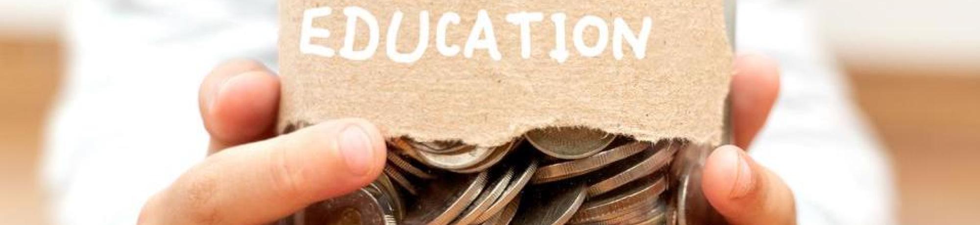 A child's hands hold a jar of coins. The Jar reads, "Education."