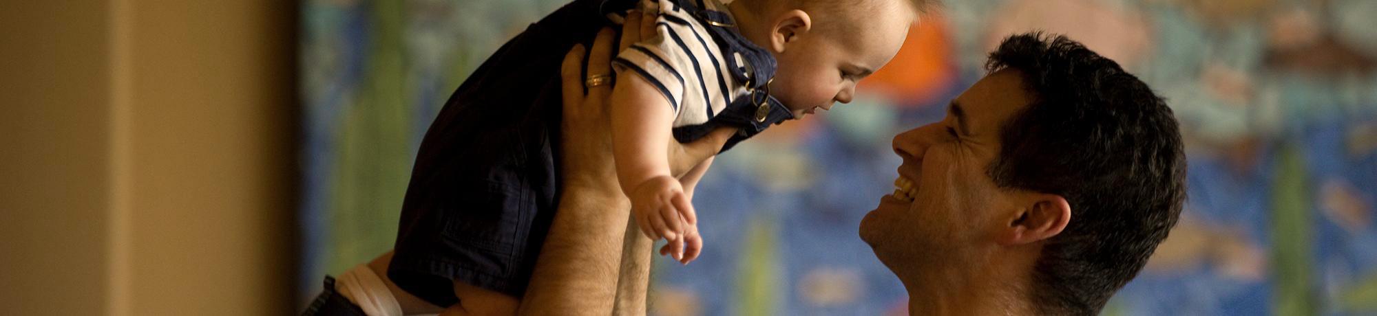 man lifting baby to look at his face