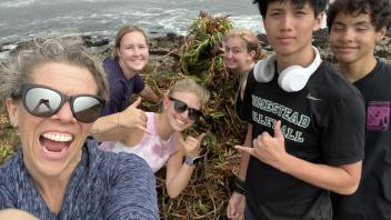 UC Davis Pre-College instructor Dr. Elise Fairbairn and students pose in front of a pile of invasive plants they removed from the reserve