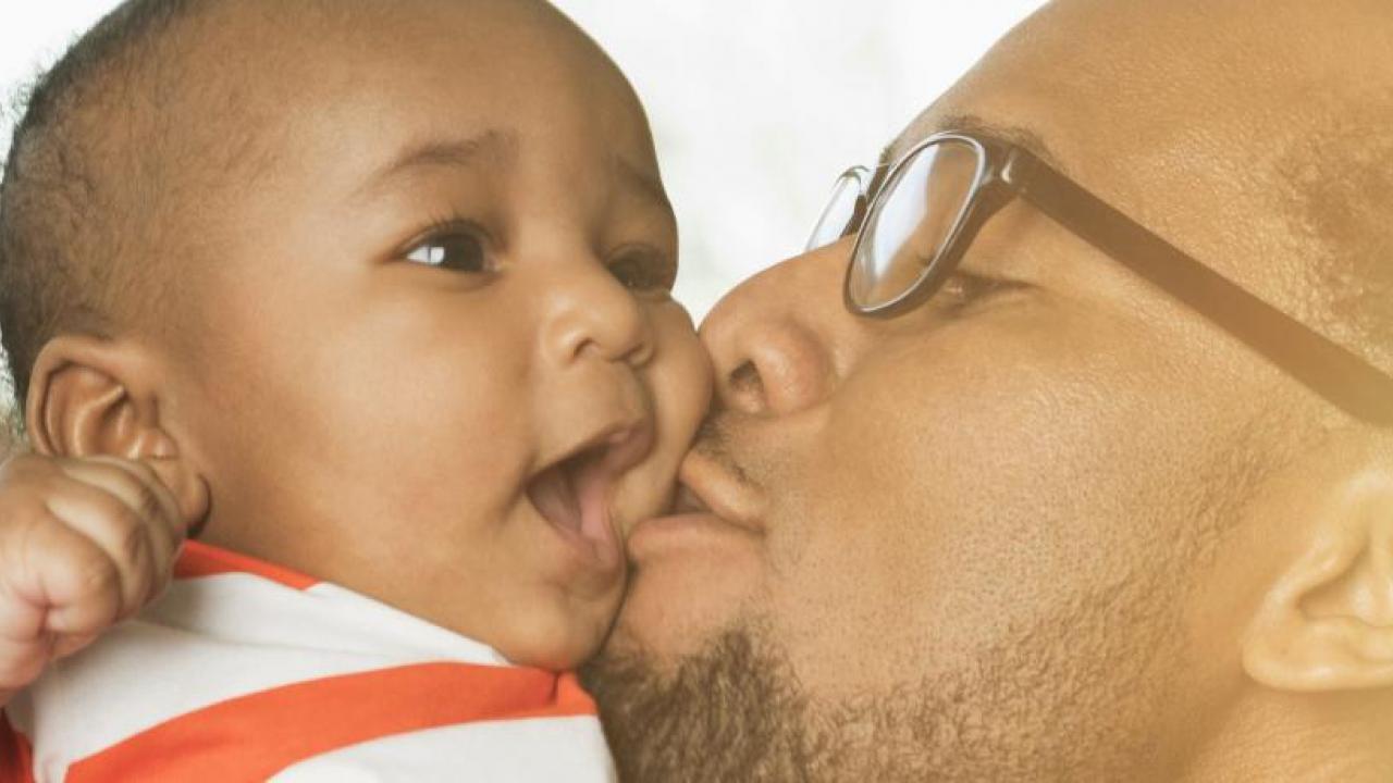 father kissing infant