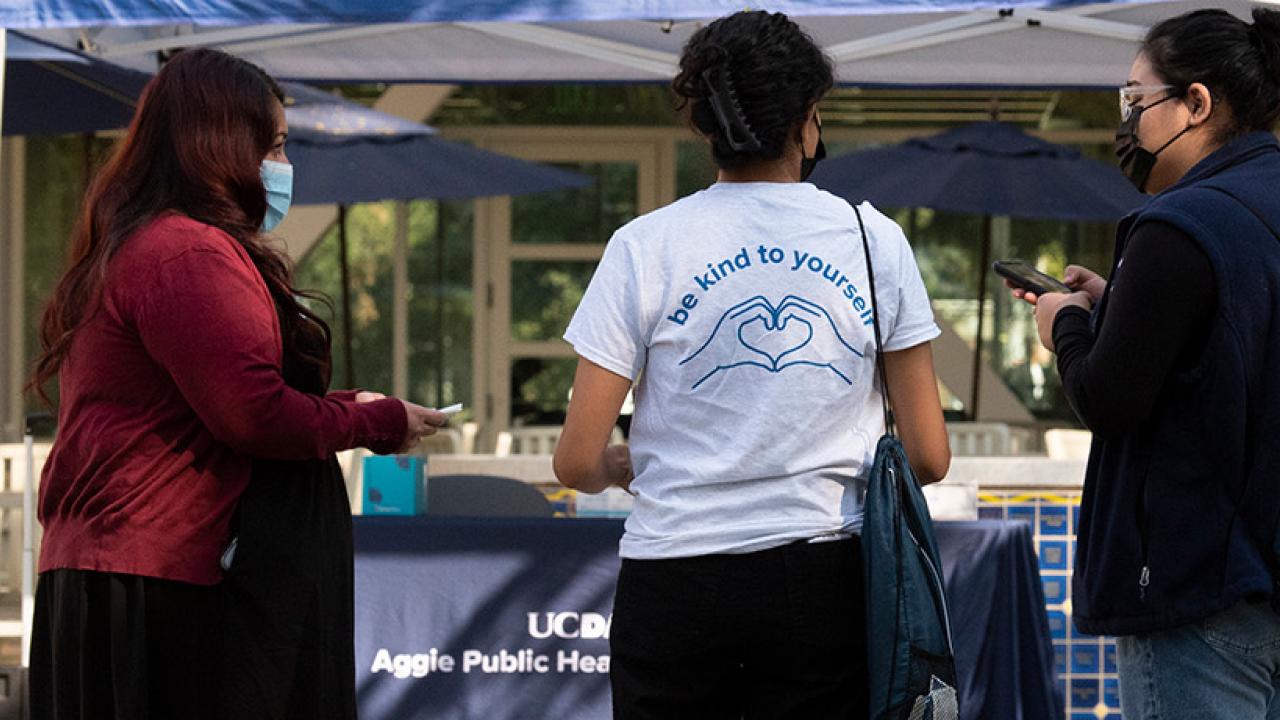 three women standing in front of Aggie Public Health booth
