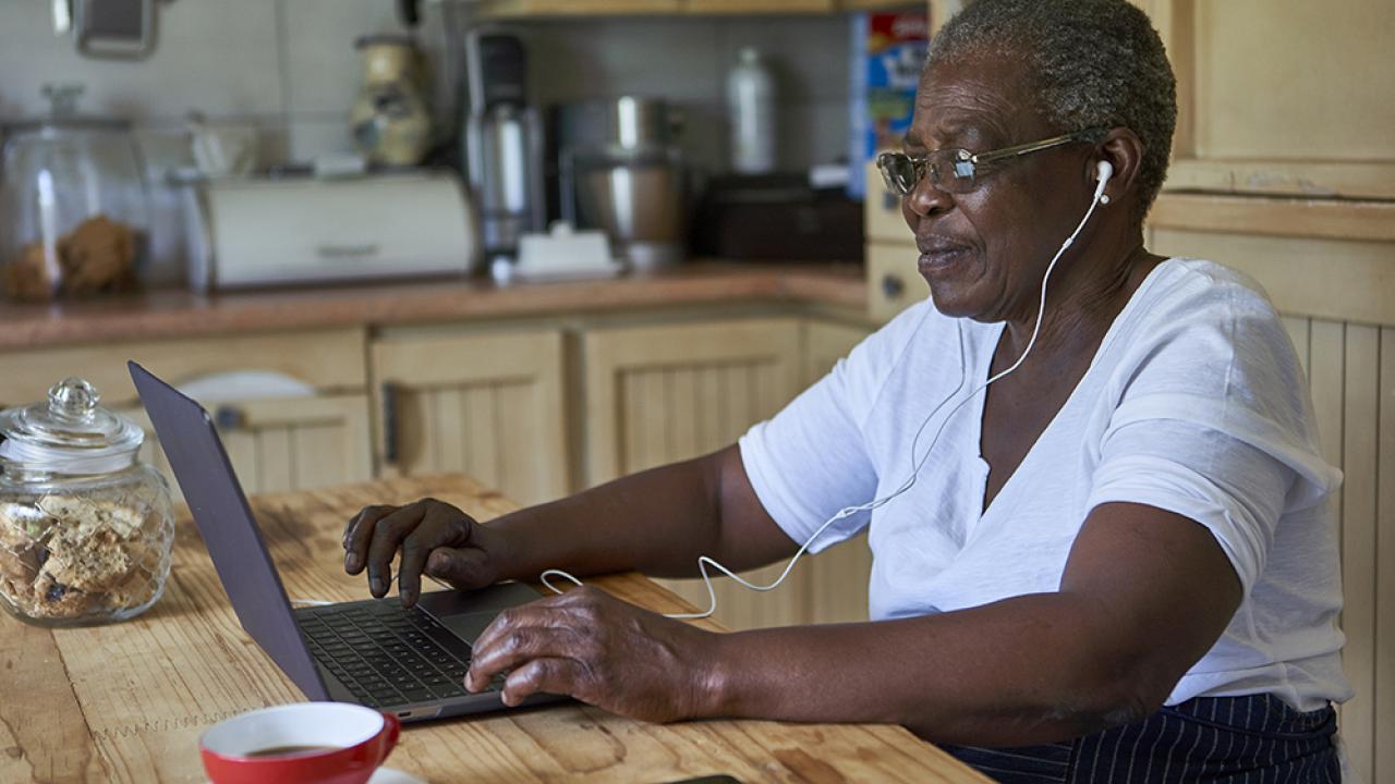 senior woman sitting at kitchen table in front of laptop