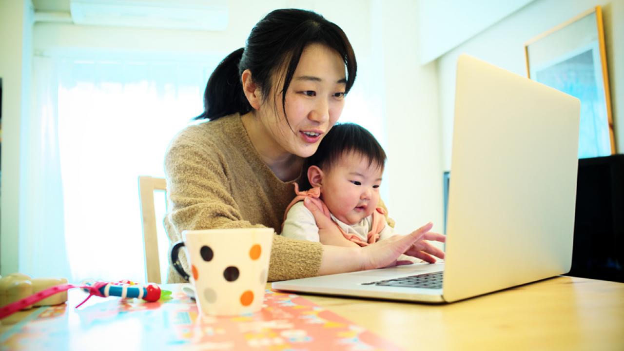 mom working from home on laptop with baby in lap