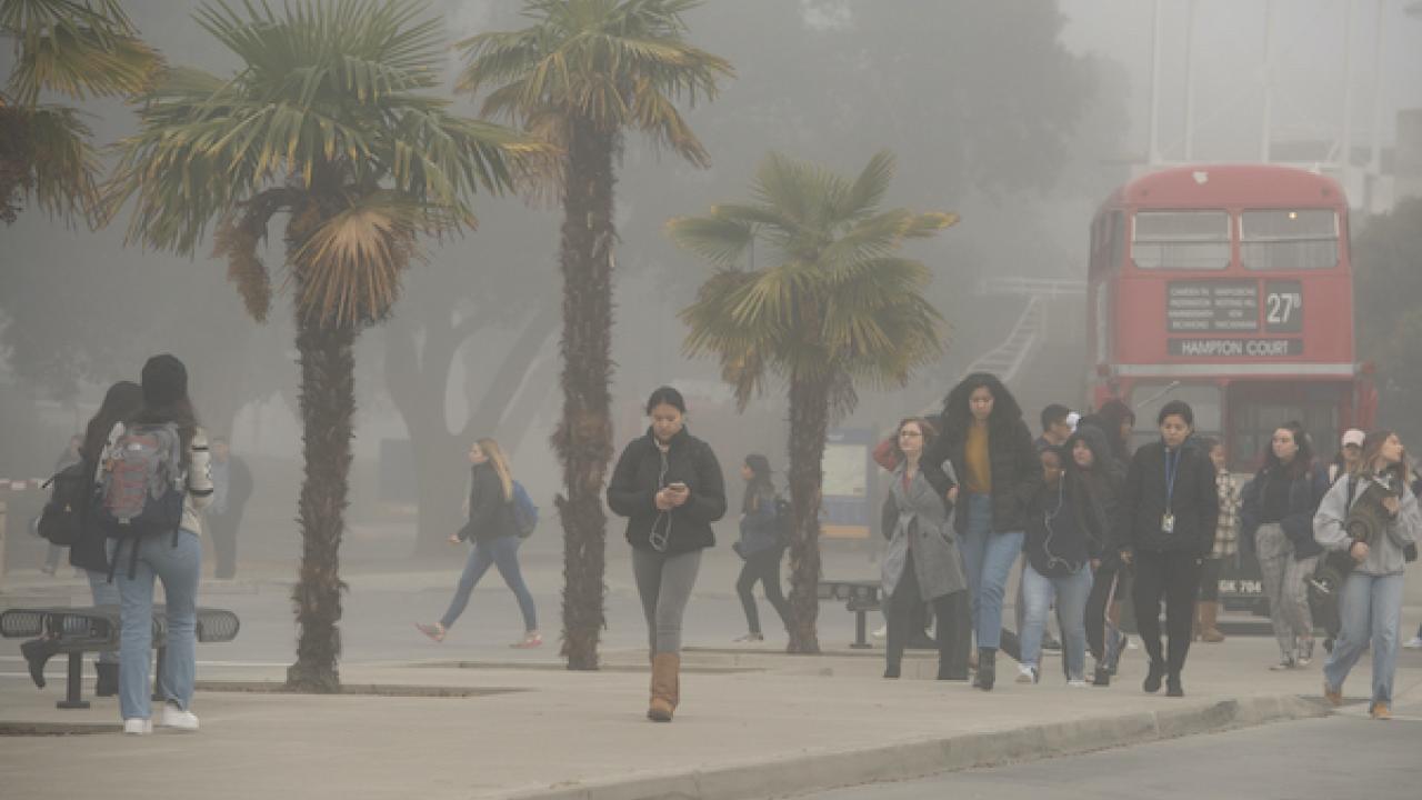 UC Davis students walk through the fog at the transportation terminal on campus