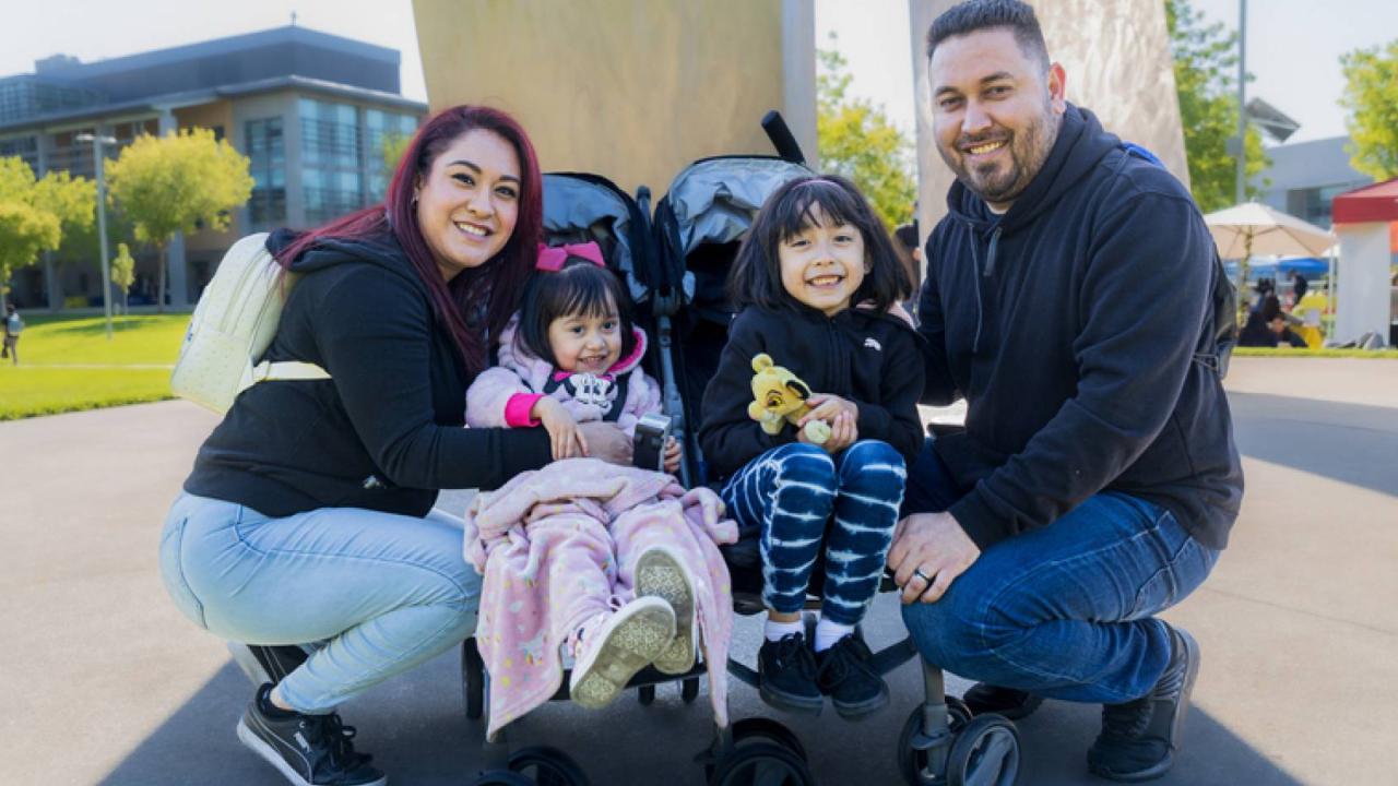 A family with two parents and two young children in a stroller.