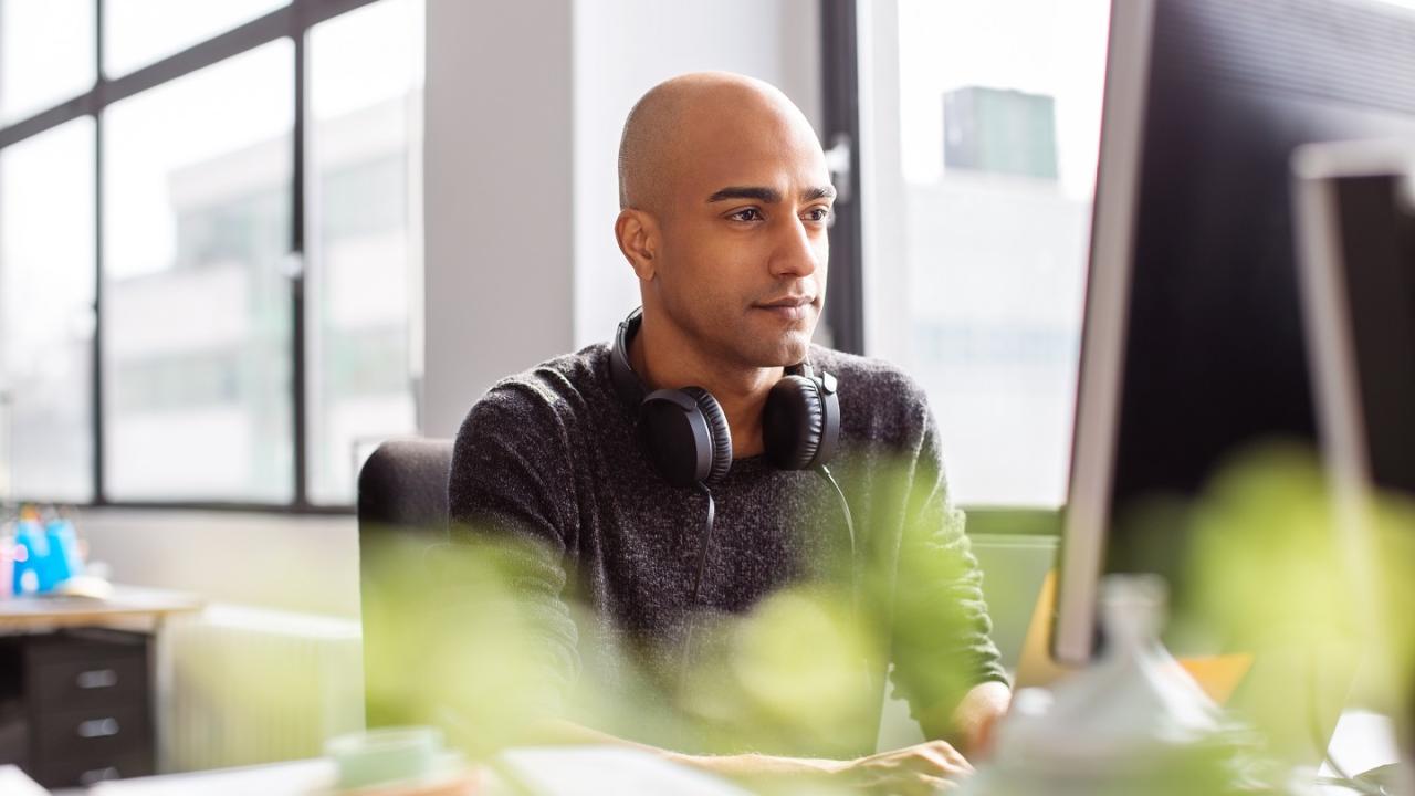 Person working at a computer with headphones around their shoulders
