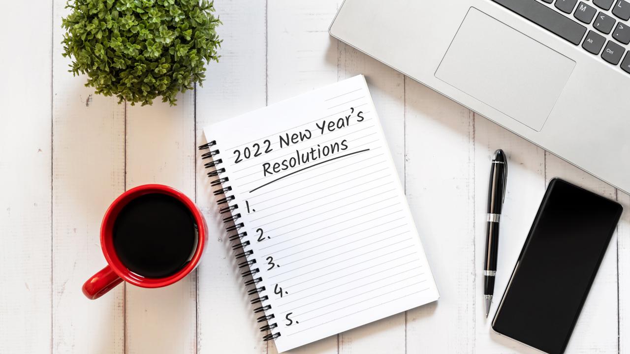 image of desk with computer and list on notepad for new year's resolutions