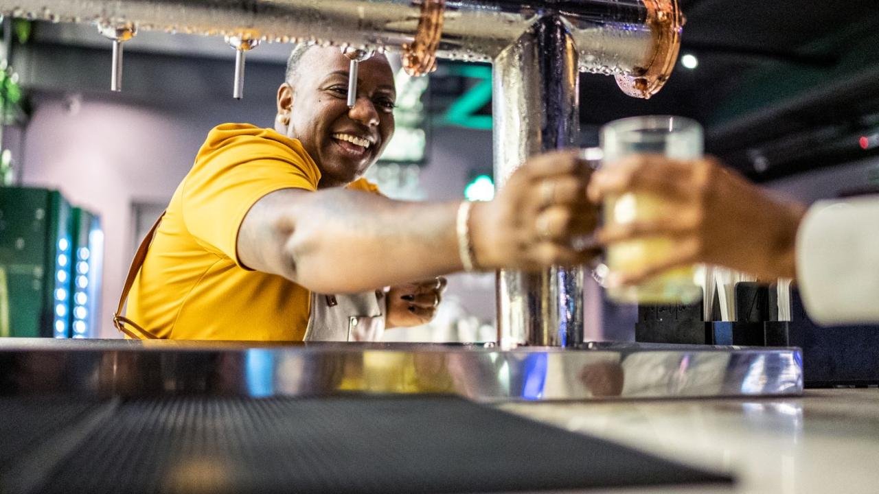 Bar tender smiling giving a drink to a customer or waiter. 