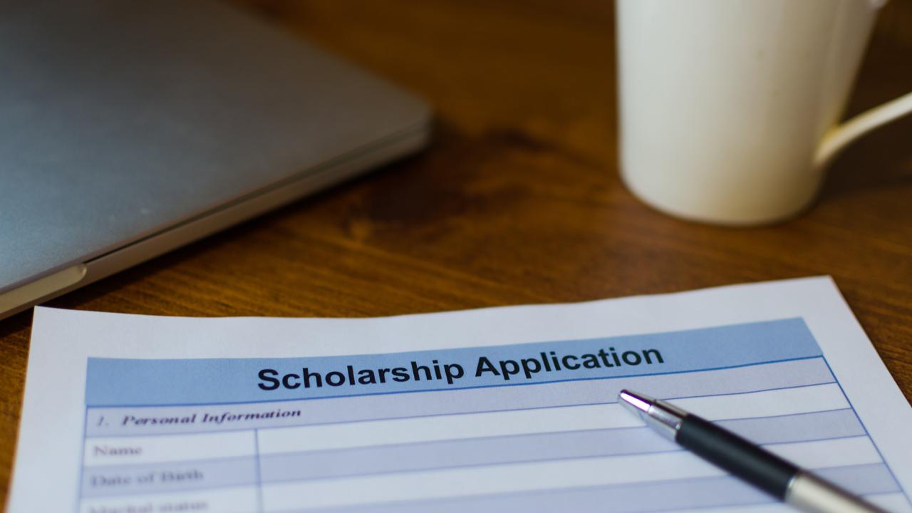 scholarship application, pen and coffee mug on desk