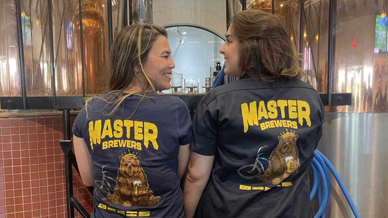 Two Master Brewers students show off their shirts at the brewery