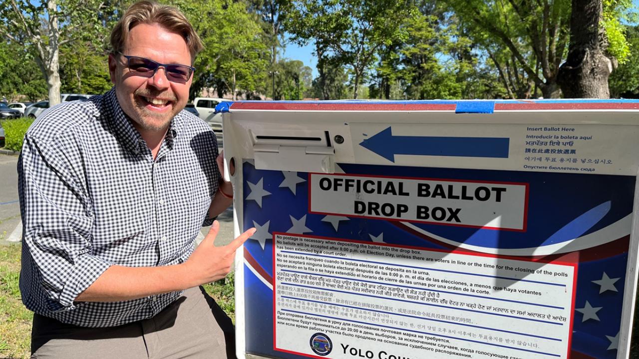Land Use and Planning Certificate Program grad Lucas Frerichs poses next to a ballot box
