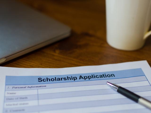 scholarship application, pen and coffee mug on desk