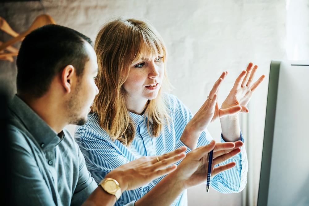 woman and man talking and gesturing at computer screen