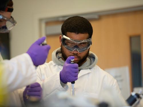 men wearing gloves and goggles working in a lab