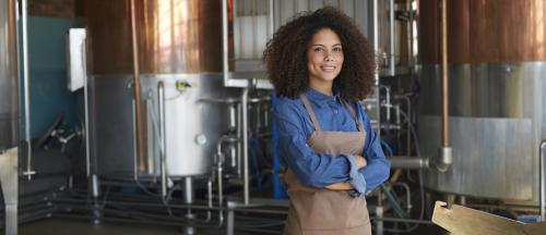 female brewer standing and smiling in brewery