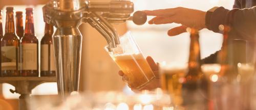 close up of barntender filling glass of beer at tap