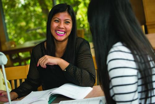 two college students studying and smiling