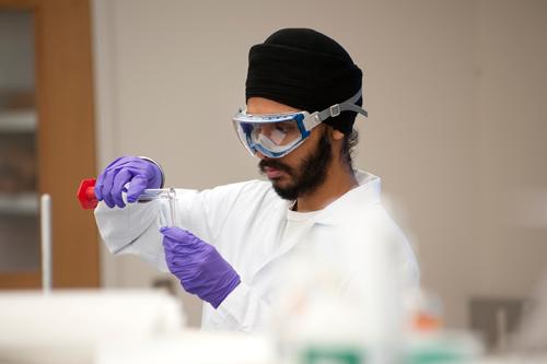 man wearing goggles and gloves working in a lab